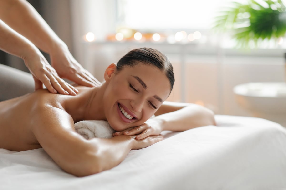 Spa Treatments. Happy young lady enjoying back massage in luxury beauty salon, wellness day at beauty center, free space