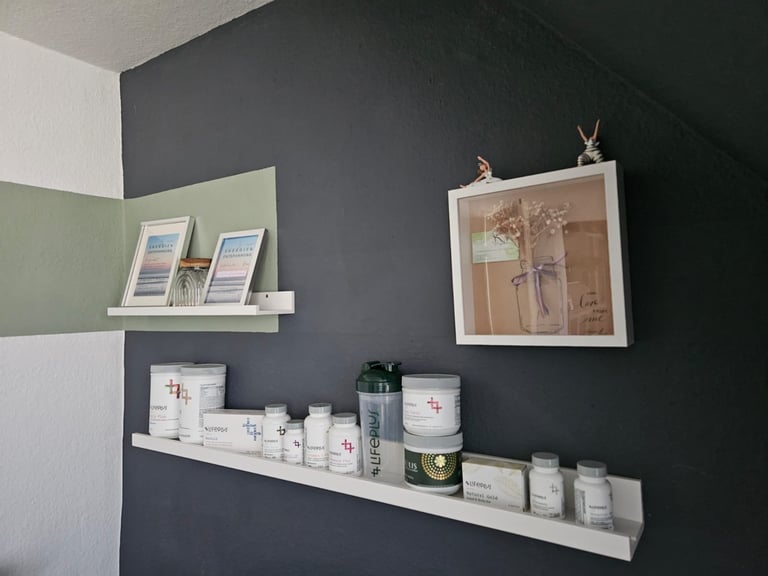 Wall-mounted white shelves with skincare and beauty products displayed on charcoal and light green painted walls